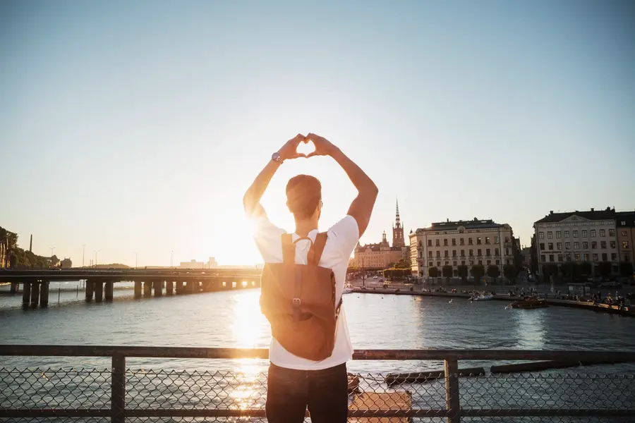 Manlig turist gör hjärtform med händerna i staden mot klar himmel